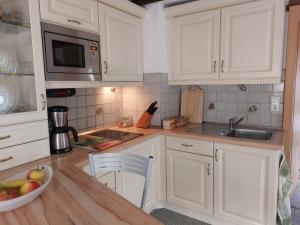 a kitchen with white cabinets and a bowl of fruit on the counter at Gerlindes Haus - inkl. Chiemgau-Karte in Siegsdorf