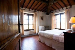 um quarto com uma cama e duas janelas em Relais Riserva di Fizzano em Castellina in Chianti
