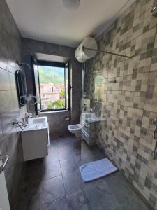 baño con lavabo y aseo y ventana en Opera apartments, en Tivat