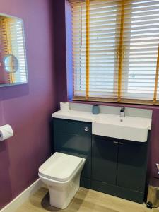 a bathroom with a toilet and a sink and a window at Almarie in Fort William