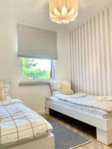 sypialnia z 2 łóżkami, oknem i żyrandolem w obiekcie APARTAMENT NA WZGÓRZU w Lidzbarku Warmińskim