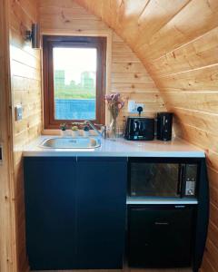 una cocina con microondas y fregadero en una cabaña en The Pods at Streamvale, en Gilnahirk