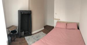um quarto com uma cama com lençóis cor-de-rosa e uma mesa em Blue house em Lincoln