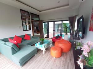 salon z niebieską kanapą i czerwonymi poduszkami w obiekcie Richly pool villa@Phitsanulok w mieście Ban Ko