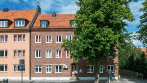 un grand bâtiment en briques avec un arbre devant lui dans l'établissement Miatorp Hotell, à Helsingborg