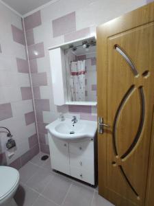 un bagno con lavandino, servizi igienici e porta di Casa Tenciu a Sînpetru