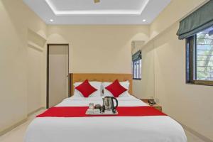 1 dormitorio con 1 cama blanca grande con almohadas rojas en Hotel Sunrise Juhu, en Bombay