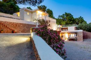 una casa con flores púrpuras delante de ella en Villa in Ibiza Town, sleeps 6 - Can Damia, en Sant Jordi