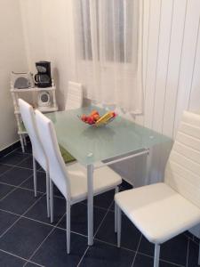 a table with white chairs and a bowl of fruit on it at Studio Luka in Crikvenica