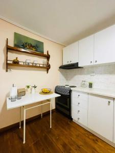 a kitchen with white cabinets and a table in it at Casa de Pera in Mytilene