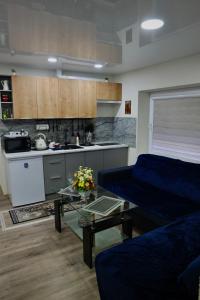 a living room with a blue couch and a kitchen at Apartament in the City Center in Rokiškis