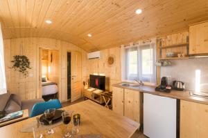 a kitchen and living room with a wooden ceiling at Roulotte Paradis: insolite, SPA privatif, piscine in Chilly