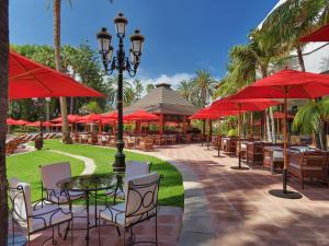 un patio con tavoli, sedie e ombrelloni rossi di Hotel Botanico y Oriental Spa Garden a Puerto de la Cruz