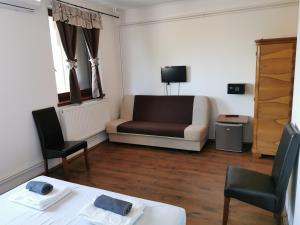 uma sala de estar com um sofá, uma mesa e cadeiras em Merlot Borhotel és Látványpince em Edelény