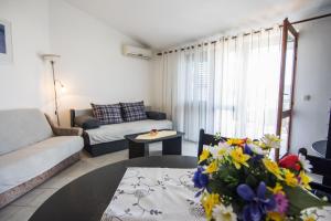 - un salon avec un canapé et une table fleurie dans l'établissement Apartments by the sea Biograd na Moru, Biograd - 12829, à Biograd na Moru