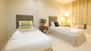 1 dormitorio con 2 camas y mesa. en UrbanView at Lacson Street Bacolod City by RedDoorz, en Bacolod