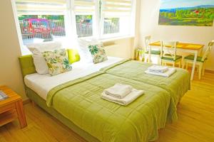 a bedroom with a green bed with towels on it at Nad Stawem in Ustroń