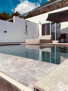 a swimming pool with an umbrella next to a house at Akrogiali Apartments in Barbati