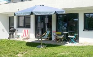 un patio con sillas y una sombrilla frente a una casa en Ferienwohnung mit Traumblick und großem Garten en Lindenberg im Allgäu