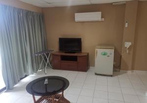 a living room with a tv and a table and a refrigerator at CORAL BAY APARTMENT 3room (Ocean apartment) in Pangkor
