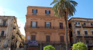 a tall building with a palm tree in front of it at Da Ale alla Cattedrale in Palermo