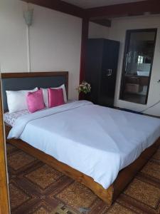 1 dormitorio con 1 cama grande con almohadas rosas en Abode Me Me Ai Haven en Cherrapunji