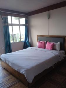 ein Schlafzimmer mit einem großen Bett mit rosa Kissen in der Unterkunft Abode Me Me Ai Haven in Cherrapunji