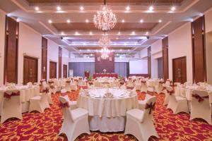 a banquet hall with white tables and chairs and a chandelier at Arion Suites Hotel Kemang in Jakarta