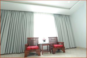 Dos sillas y una mesa frente a un gran ventanal. en Tan Truong Son Hotel, en Dong Hoi