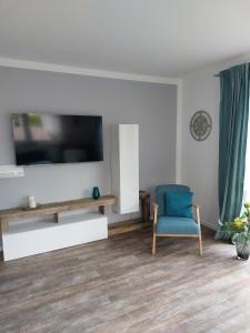 a living room with a tv and a blue chair at Ferienwohnung Finja - a70682 in Dreschvitz
