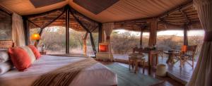 Elewana Lewa Safari Camp في Meru: غرفة نوم في خيمة مع سرير وطاولة