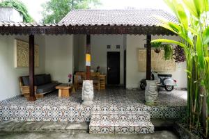 a house with a porch with a couch and a motorcycle at Ari Cottages Ubud in Ubud