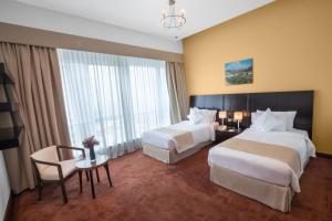 a hotel room with two beds and a table and chairs at City Premiere Hotel Apartments - Dubai in Dubai