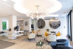 a living room with a chandelier and a table and chairs at Hôtel Dress Code in Paris