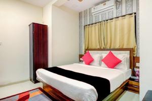 a bedroom with a large bed with red pillows at Hotel De Classico Juhu in Mumbai