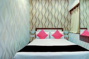 a bedroom with a bed with pink pillows at Hotel De Classico Juhu in Mumbai