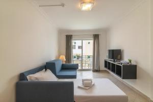 a living room with a blue couch and a tv at Smy Santa Eulalia Algarve in Albufeira