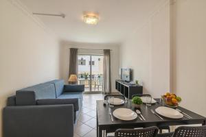 a living room with a blue couch and a table at Smy Santa Eulalia Algarve in Albufeira