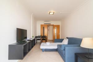 Smy Santa Eulalia Algarve في ألبوفيرا: غرفة معيشة بها أريكة زرقاء وتلفزيون