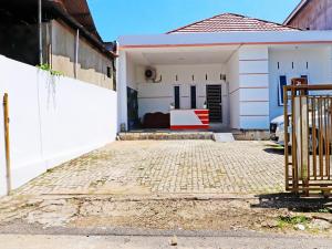 a white house with a gate and a driveway at OYO 91408 Kas Residence Syariah in Jambi