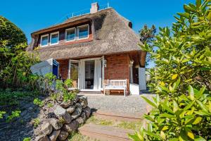 a thatch roof house with a bench in front of it at Perle am Watt in List