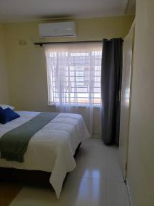 um quarto com uma cama grande e uma janela em Kasuda three bedrooms house in Livingstone em Livingstone