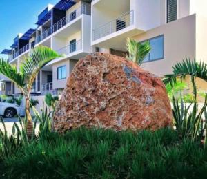 a large rock sitting in the grass in front of a building at New Luxury 2 Bedroom Apartment with Pool - close to Flic-en-Flac Beach in Flic-en-Flac