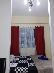 ein Schlafzimmer mit einem Bett mit roten Vorhängen und einem Fenster in der Unterkunft Pet Friendly Transient along Ortigas Extension in Cainta