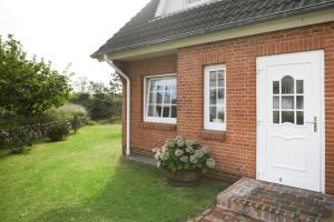 a brick house with a white door and a yard at Friesenkoje in List