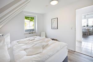 een witte slaapkamer met een groot bed en een eetkamer bij Hafenblick Haus Senhuk in List