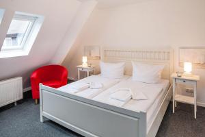 a bedroom with a white bed and a red chair at Strandgut in List
