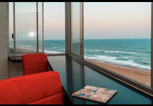 a red chair in a room with a view of the ocean at Mai Paradise in Kingsburgh