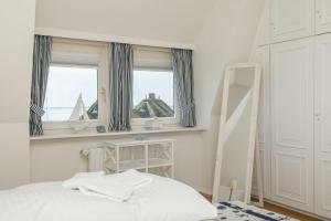 a white bedroom with a bed and two windows at Strandhaus in List