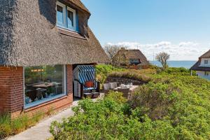 a house with a thatched roof and a patio at Strandhaus in List